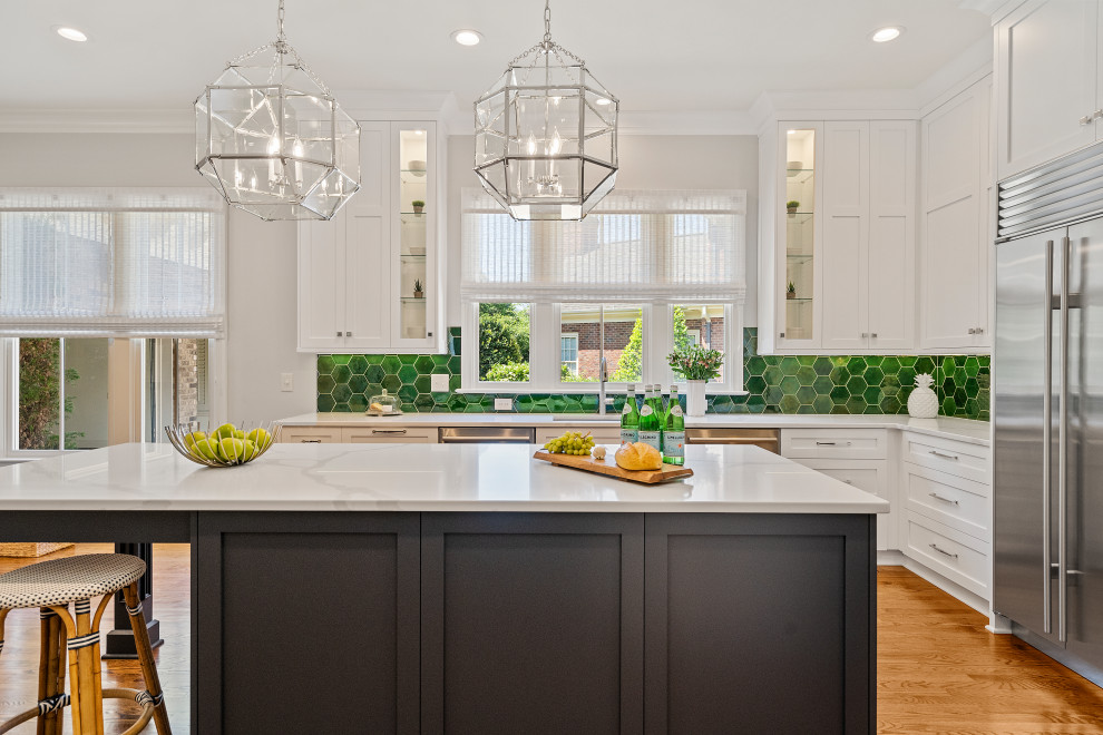 This is an example of a large traditional l-shaped open plan kitchen in Minneapolis with a built-in sink, beaded cabinets, white cabinets, quartz worktops, green splashback, ceramic splashback, stainless steel appliances, light hardwood flooring, an island, brown floors and white worktops.