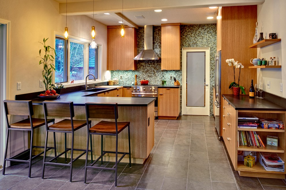 Example of a minimalist u-shaped porcelain tile kitchen design in Portland with an undermount sink, flat-panel cabinets, medium tone wood cabinets, granite countertops, multicolored backsplash, glass tile backsplash, stainless steel appliances and a peninsula