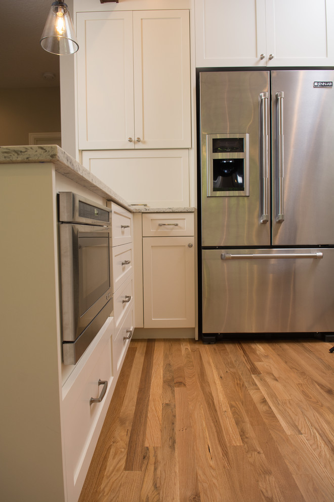Exempel på ett mellanstort klassiskt kök, med en undermonterad diskho, skåp i shakerstil, vita skåp, bänkskiva i kvartsit, vitt stänkskydd, stänkskydd i tunnelbanekakel, rostfria vitvaror, mellanmörkt trägolv och en halv köksö