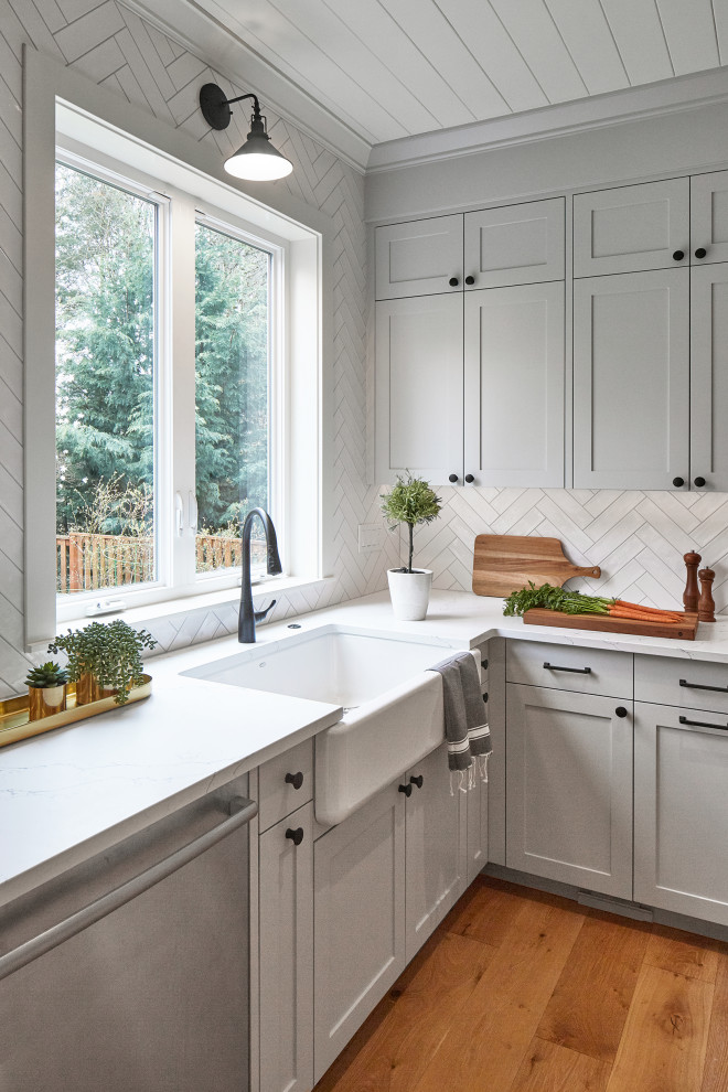 Open concept kitchen - mid-sized cottage u-shaped light wood floor and exposed beam open concept kitchen idea in Portland with a farmhouse sink, flat-panel cabinets, gray cabinets, quartz countertops, white backsplash, ceramic backsplash, paneled appliances, an island and white countertops