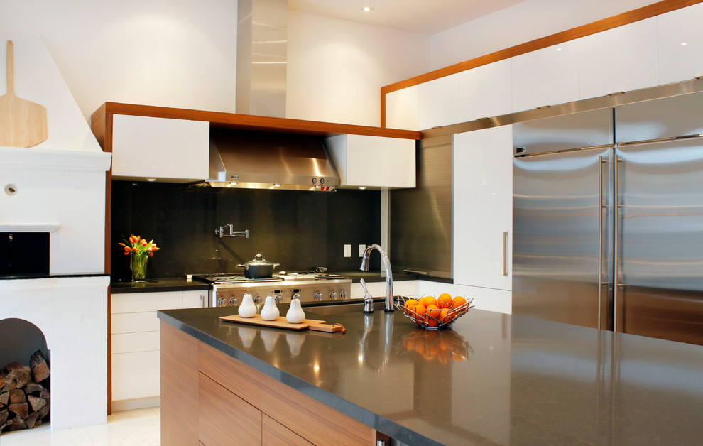 Trendy l-shaped eat-in kitchen photo in Toronto with flat-panel cabinets, white cabinets, stainless steel appliances, black backsplash, an undermount sink and quartz countertops