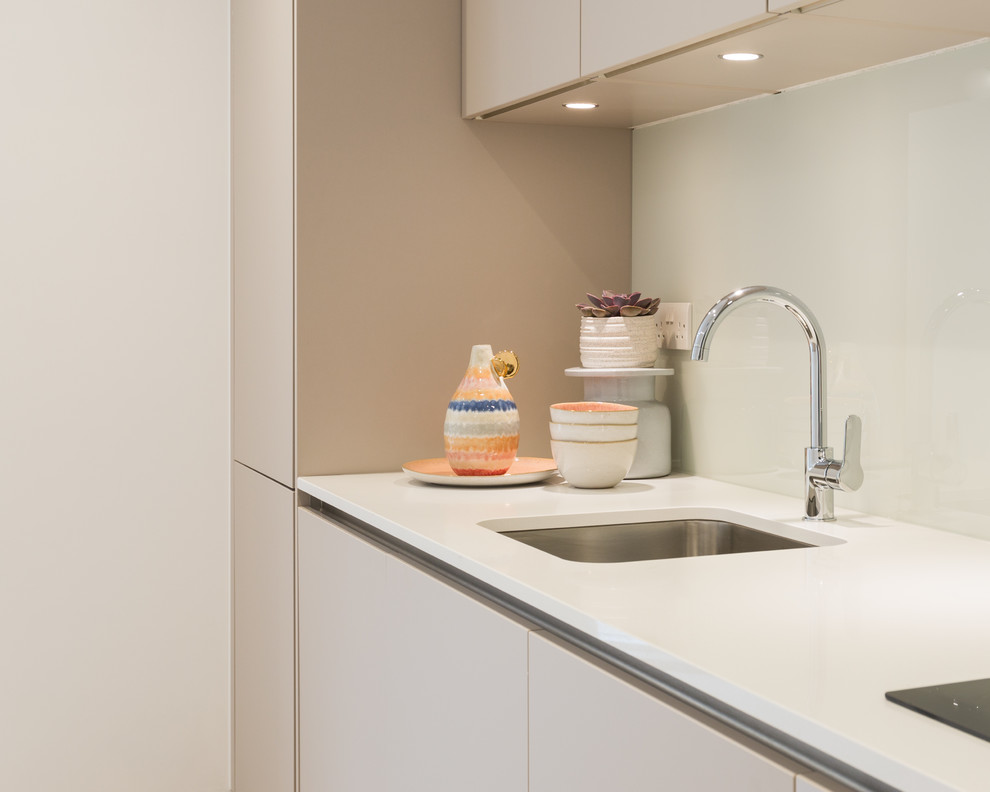 Exempel på ett mellanstort modernt vit linjärt vitt kök med öppen planlösning, med en undermonterad diskho, släta luckor, bruna skåp, bänkskiva i kvartsit, glaspanel som stänkskydd, integrerade vitvaror, laminatgolv och brunt golv