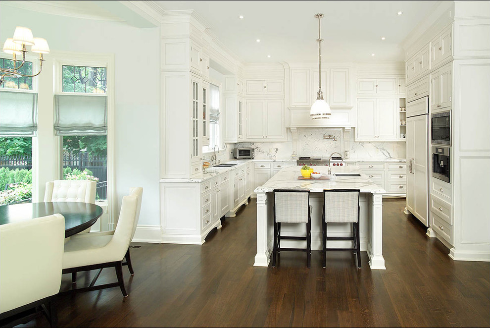 Klassische Küche in L-Form mit weißen Schränken, Marmor-Arbeitsplatte, Küchenrückwand in Weiß, Rückwand aus Stein, Elektrogeräten mit Frontblende und Mauersteinen in Toronto