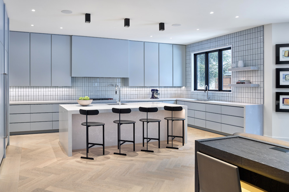 Immagine di una cucina contemporanea con lavello sottopiano, ante lisce, ante grigie, paraspruzzi bianco, parquet chiaro, pavimento beige e top bianco