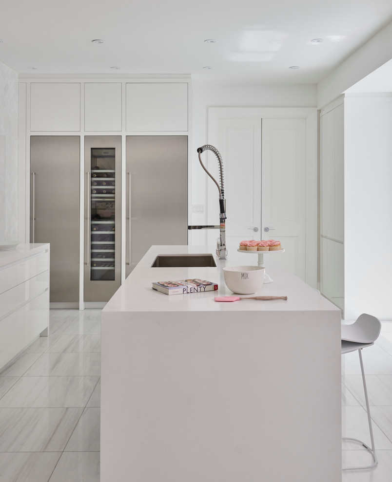 Inspiration for a large vintage l-shaped kitchen/diner in Toronto with a submerged sink, flat-panel cabinets, white cabinets, composite countertops, white splashback, ceramic splashback, stainless steel appliances, marble flooring and an island.
