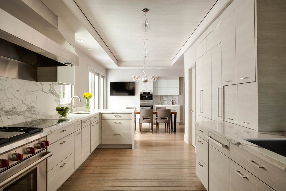Exempel på ett modernt u-kök, med släta luckor, marmorbänkskiva, en halv köksö, en undermonterad diskho, grå skåp, vitt stänkskydd, stänkskydd i sten, rostfria vitvaror och mellanmörkt trägolv