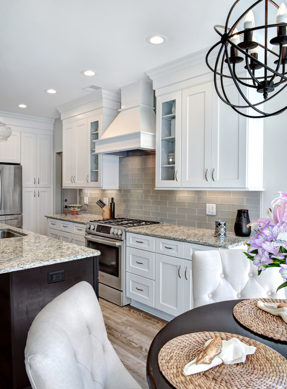 Eat-in kitchen - large contemporary l-shaped porcelain tile and brown floor eat-in kitchen idea in Charleston with an undermount sink, shaker cabinets, white cabinets, granite countertops, gray backsplash, glass tile backsplash, stainless steel appliances and an island