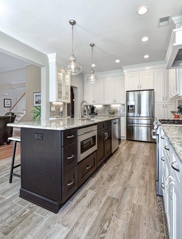 Example of a large trendy l-shaped porcelain tile and brown floor eat-in kitchen design in Charleston with an undermount sink, shaker cabinets, white cabinets, granite countertops, gray backsplash, glass tile backsplash, stainless steel appliances and an island