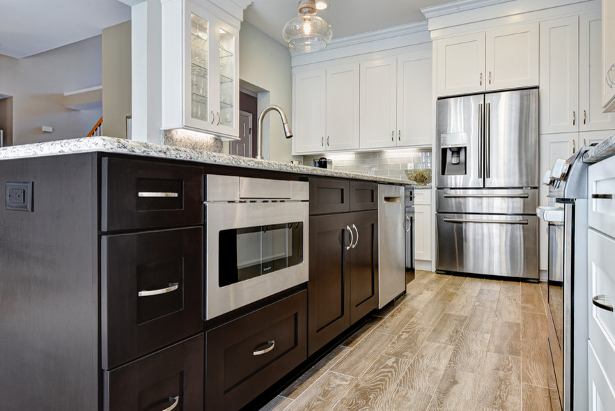 Example of a large trendy l-shaped porcelain tile and brown floor eat-in kitchen design in Charleston with an undermount sink, shaker cabinets, white cabinets, granite countertops, gray backsplash, glass tile backsplash, stainless steel appliances and an island