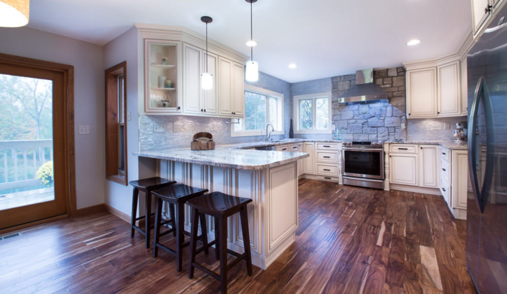 Exempel på ett mellanstort klassiskt grå grått kök, med en undermonterad diskho, luckor med infälld panel, vita skåp, granitbänkskiva, grått stänkskydd, stänkskydd i stenkakel, rostfria vitvaror, mörkt trägolv, en köksö och brunt golv