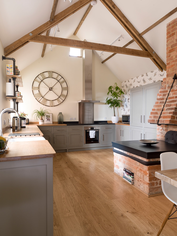 Design ideas for a medium sized rural grey and cream u-shaped open plan kitchen in Other with a belfast sink, recessed-panel cabinets, grey cabinets, wood worktops, beige floors, brown worktops, integrated appliances, medium hardwood flooring and no island.