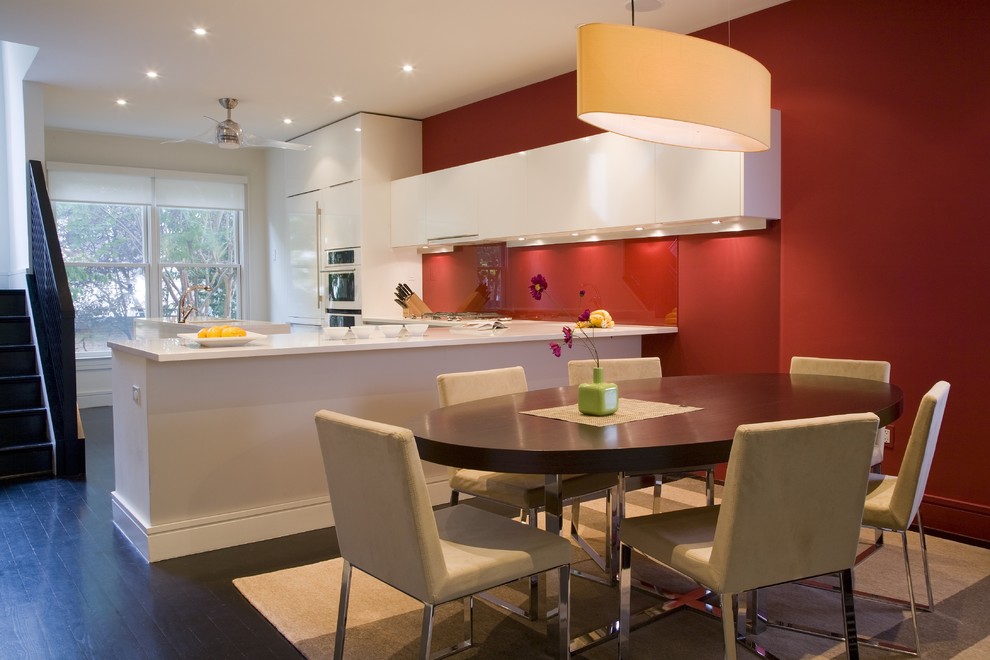 Foto di una cucina moderna con ante lisce, ante bianche, paraspruzzi rosso, paraspruzzi con lastra di vetro e elettrodomestici da incasso