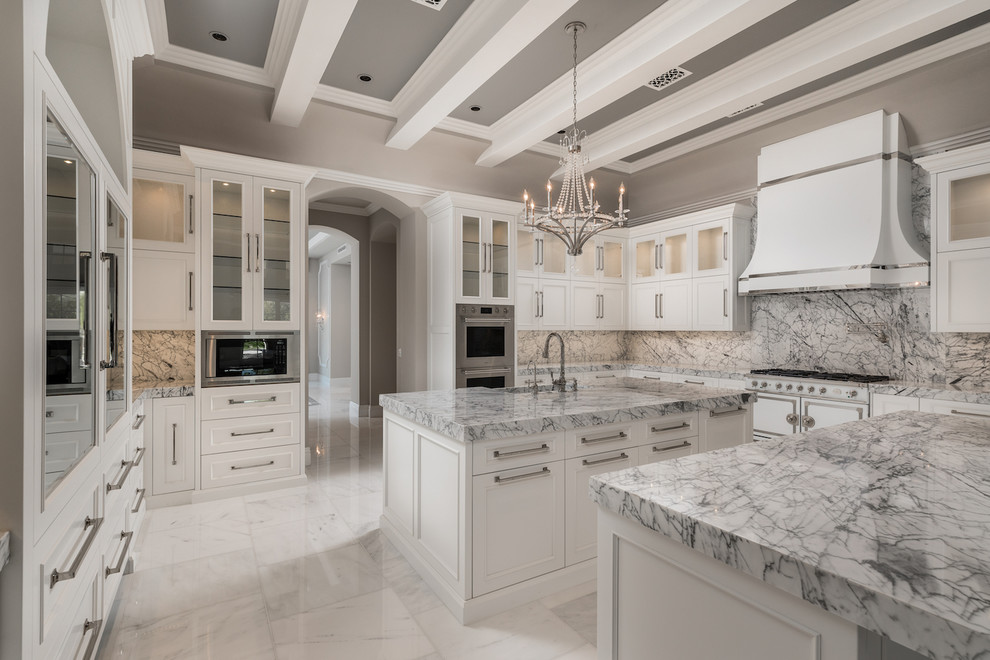 Huge tuscan u-shaped marble floor, multicolored floor and exposed beam enclosed kitchen photo in Phoenix with a farmhouse sink, recessed-panel cabinets, white cabinets, marble countertops, multicolored backsplash, marble backsplash, stainless steel appliances, two islands and multicolored countertops
