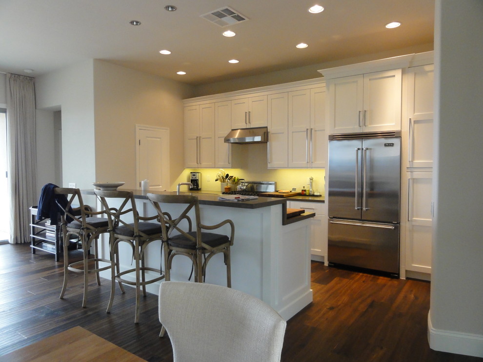 Example of a transitional galley open concept kitchen design in Las Vegas with a single-bowl sink, shaker cabinets, white cabinets, quartz countertops, white backsplash and stainless steel appliances
