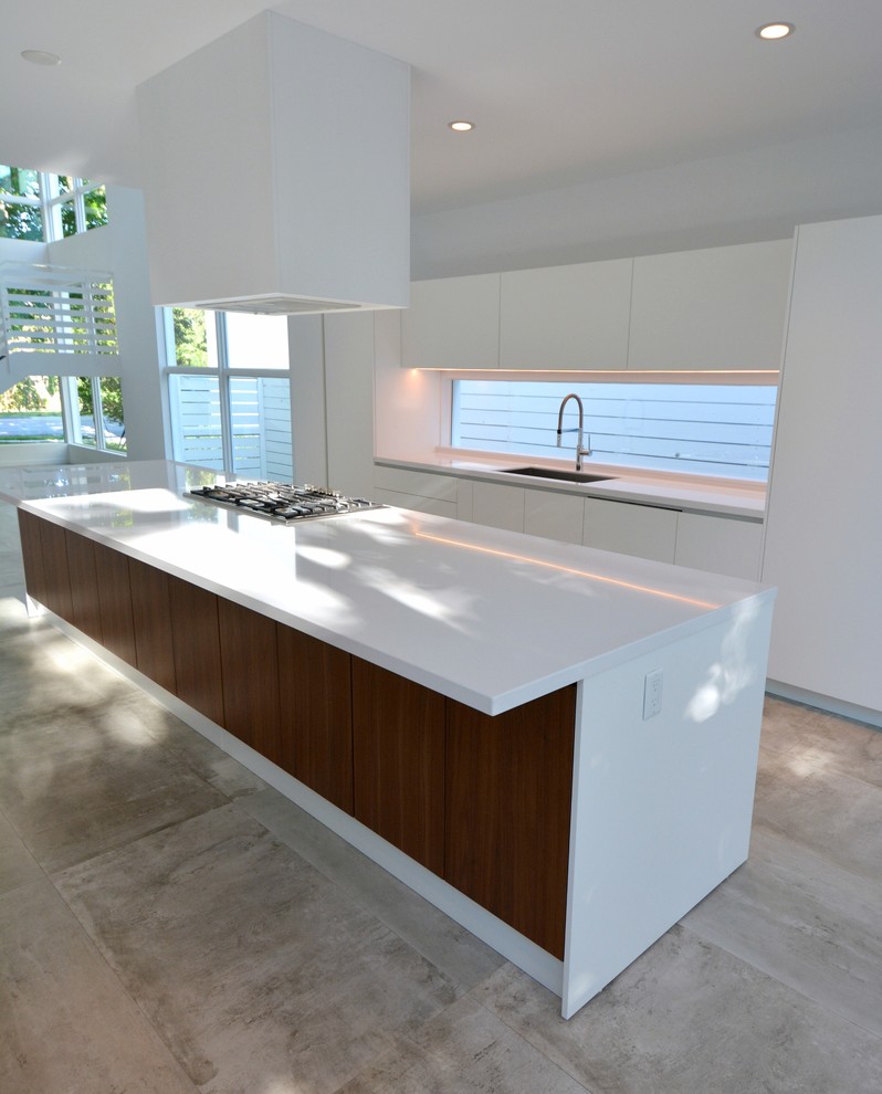 Bild på ett stort funkis linjärt kök och matrum, med släta luckor, vita skåp, bänkskiva i kvartsit, en köksö, en undermonterad diskho, fönster som stänkskydd, rostfria vitvaror, cementgolv och grått golv