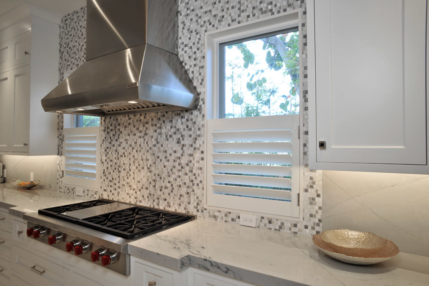 マイアミにある高級な中くらいなトランジショナルスタイルのおしゃれなキッチン (シェーカースタイル扉のキャビネット、白いキャビネット、大理石カウンター、白いキッチンパネル、大理石のキッチンパネル、シルバーの調理設備) の写真