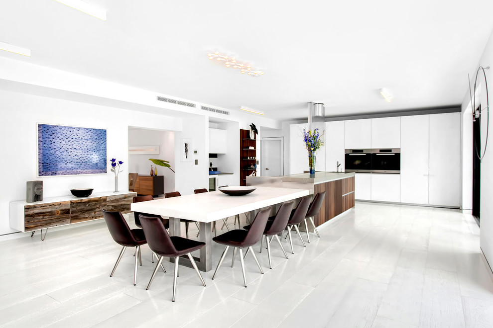 Foto de cocina comedor minimalista con armarios con paneles lisos, puertas de armario blancas, electrodomésticos de acero inoxidable y una isla
