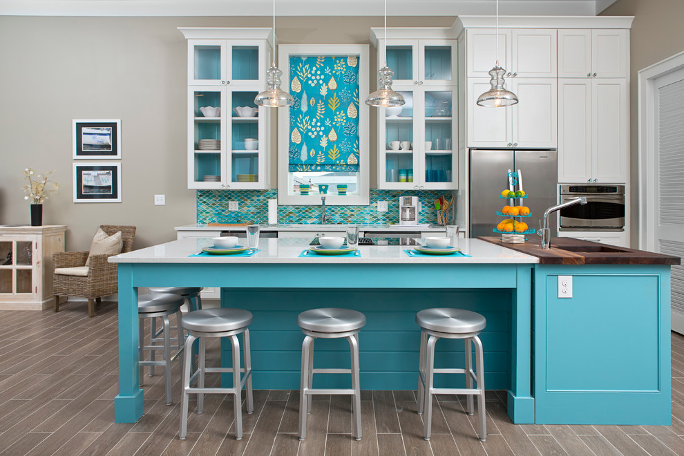 Moderne Küche mit Arbeitsplatte aus Holz, Glasfronten, weißen Schränken, Rückwand aus Mosaikfliesen und Küchengeräten aus Edelstahl in Miami