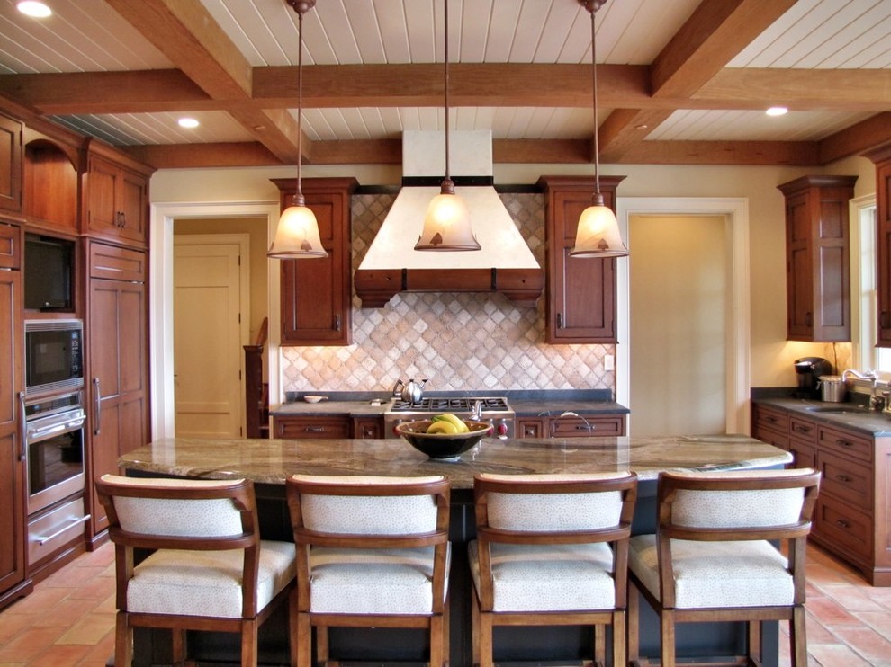 Klassisk inredning av ett stort kök, med en dubbel diskho, luckor med infälld panel, skåp i mörkt trä, granitbänkskiva, beige stänkskydd, rostfria vitvaror, tegelgolv och en köksö