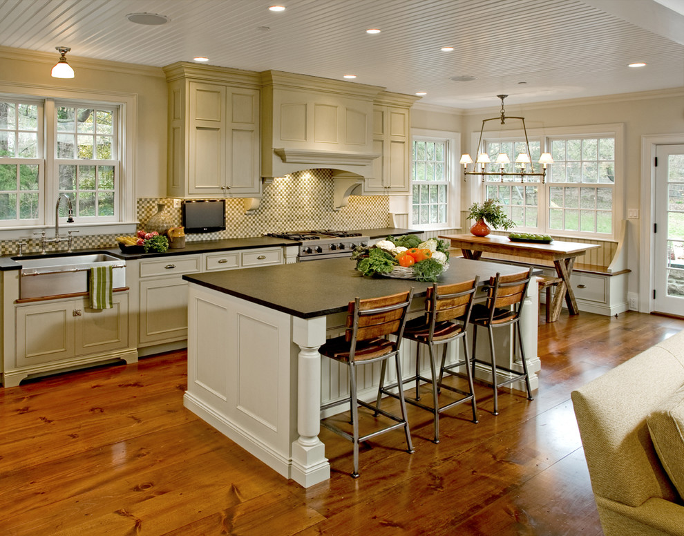 Eat-in kitchen - large traditional l-shaped medium tone wood floor eat-in kitchen idea in Philadelphia with a farmhouse sink, recessed-panel cabinets, beige cabinets, soapstone countertops, multicolored backsplash, mosaic tile backsplash, stainless steel appliances and an island