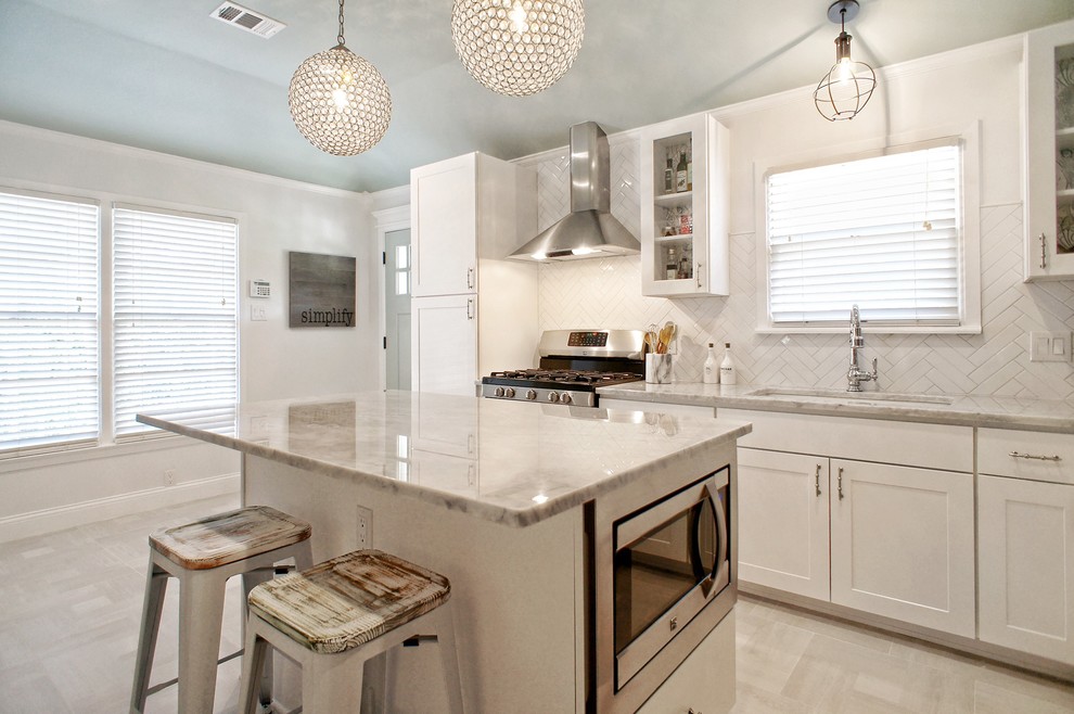 Example of a mid-sized cottage chic l-shaped porcelain tile and beige floor enclosed kitchen design in Dallas with an undermount sink, shaker cabinets, white cabinets, marble countertops, white backsplash, stainless steel appliances, an island and porcelain backsplash