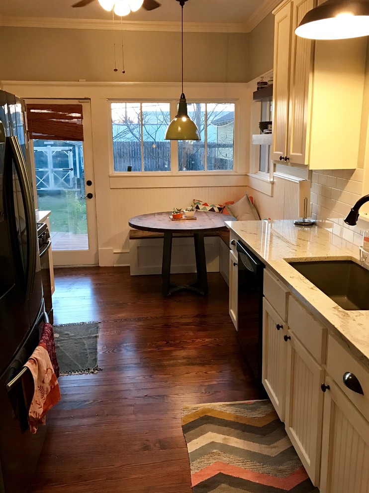 This is an example of a medium sized vintage galley kitchen/diner in Dallas with a submerged sink, beaded cabinets, white cabinets, granite worktops, white splashback, metro tiled splashback, black appliances, medium hardwood flooring, no island and brown floors.