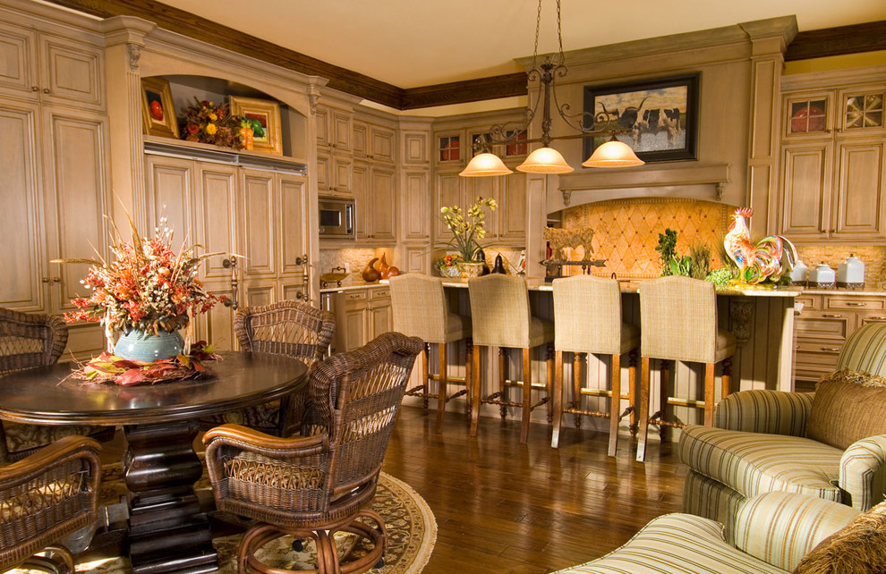 Example of a large tuscan medium tone wood floor eat-in kitchen design in Other with raised-panel cabinets, quartzite countertops, paneled appliances, an island and beige backsplash