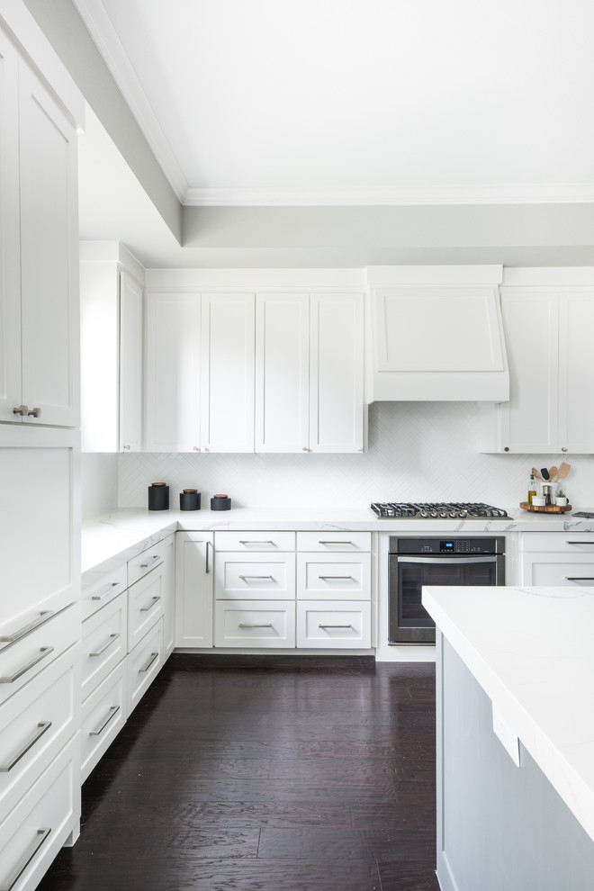 Idéer för ett stort klassiskt vit kök, med en undermonterad diskho, skåp i shakerstil, vita skåp, bänkskiva i kvartsit, vitt stänkskydd, stänkskydd i keramik, rostfria vitvaror, mörkt trägolv, en köksö och brunt golv