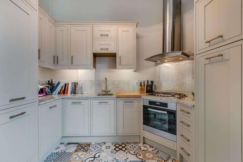 Geschlossene Klassische Küche ohne Insel in U-Form mit Schrankfronten im Shaker-Stil, weißen Schränken, Küchenrückwand in Weiß und buntem Boden in London