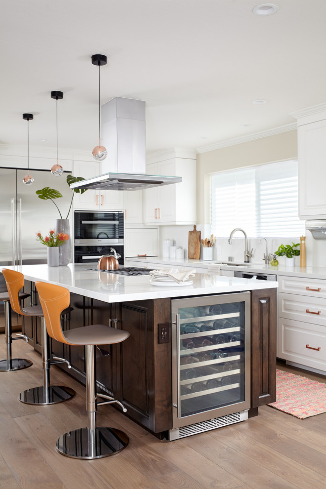 Design ideas for a traditional l-shaped kitchen in Other with a submerged sink, raised-panel cabinets, white cabinets, white splashback, stainless steel appliances, medium hardwood flooring, an island, brown floors and white worktops.