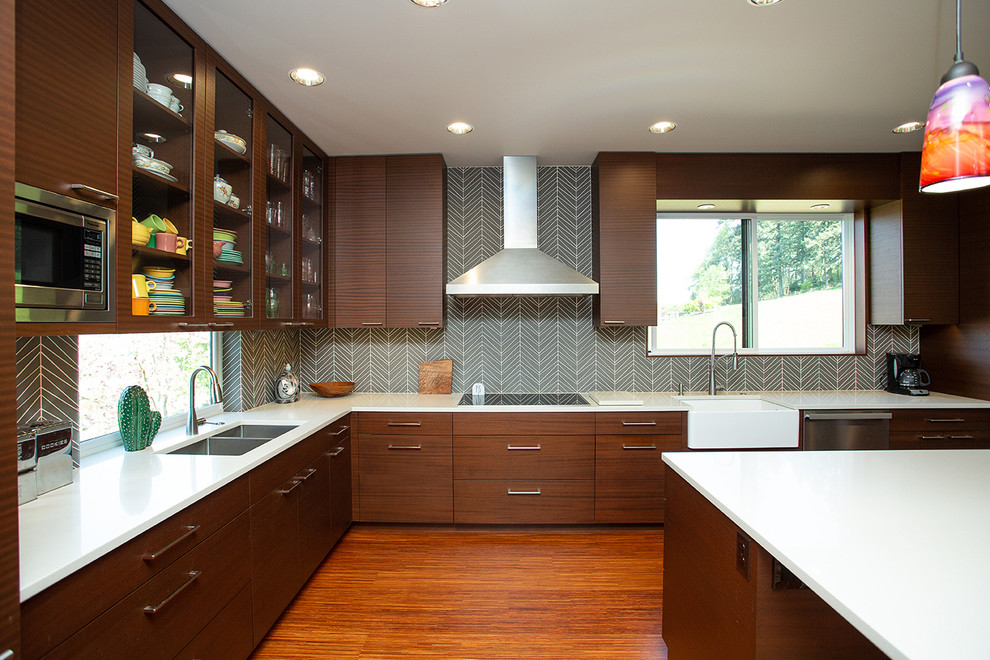 Immagine di una grande cucina minimalista con lavello a doppia vasca, ante marroni, paraspruzzi verde, elettrodomestici da incasso, pavimento in legno massello medio, pavimento marrone e top bianco