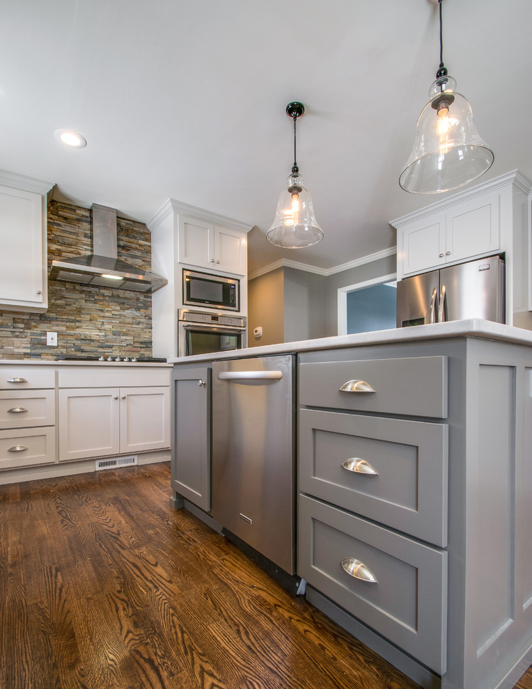 Enclosed kitchen - mid-sized traditional l-shaped dark wood floor enclosed kitchen idea in Nashville with an undermount sink, recessed-panel cabinets, gray cabinets, quartz countertops, brown backsplash, stone tile backsplash, stainless steel appliances and an island