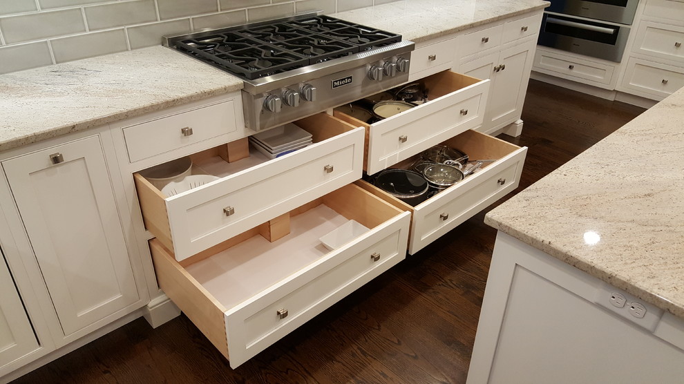 Example of a large transitional l-shaped medium tone wood floor open concept kitchen design in Philadelphia with an undermount sink, recessed-panel cabinets, white cabinets, quartzite countertops, green backsplash, ceramic backsplash, paneled appliances and two islands