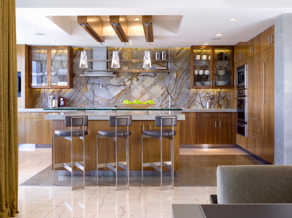 Photo of a large contemporary l-shaped open plan kitchen in Miami with glass-front cabinets, medium wood cabinets, brown splashback, stone slab splashback, stainless steel appliances, an island, quartz worktops, limestone flooring and white floors.