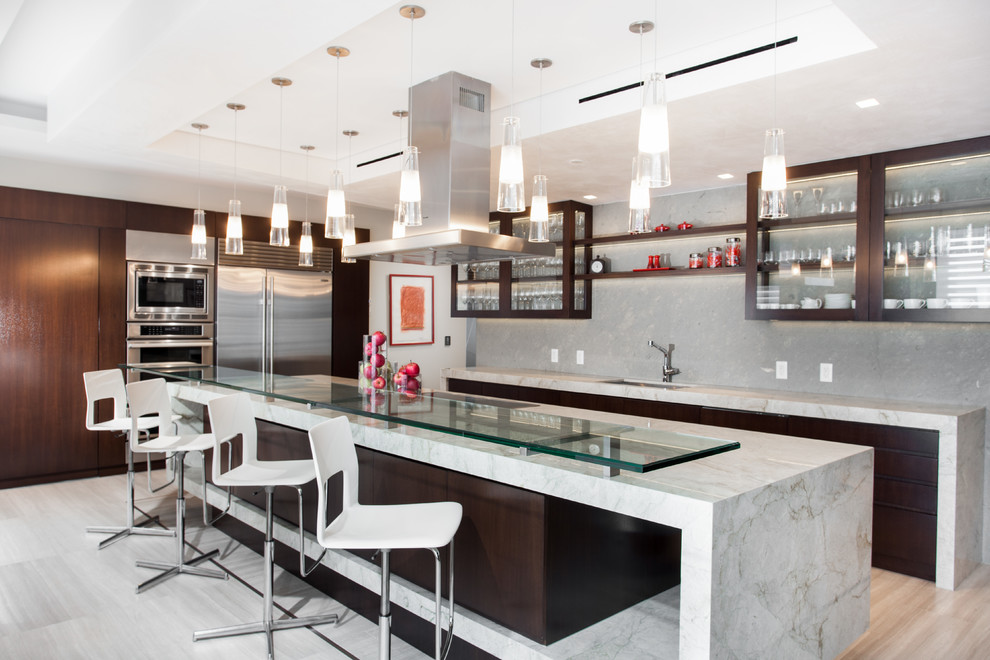 Moderne Küche mit Unterbauwaschbecken, Glasfronten, dunklen Holzschränken, Küchenrückwand in Grau, Küchengeräten aus Edelstahl, hellem Holzboden und Kücheninsel in Miami