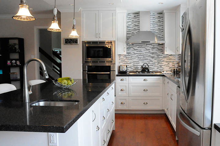 Example of a mid-sized trendy u-shaped medium tone wood floor and brown floor eat-in kitchen design in Vancouver with an undermount sink, shaker cabinets, gray backsplash, stainless steel appliances, an island, white cabinets and terrazzo countertops