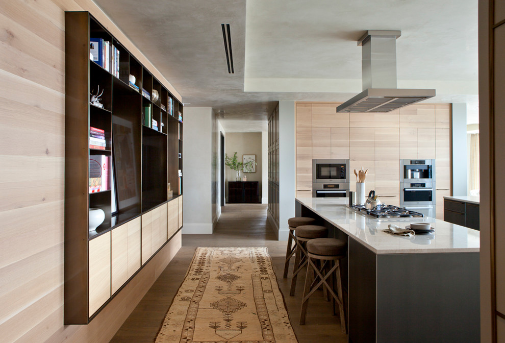 This is an example of an expansive contemporary u-shaped kitchen/diner in Austin with a submerged sink, flat-panel cabinets, light wood cabinets, marble worktops, integrated appliances, medium hardwood flooring and multiple islands.