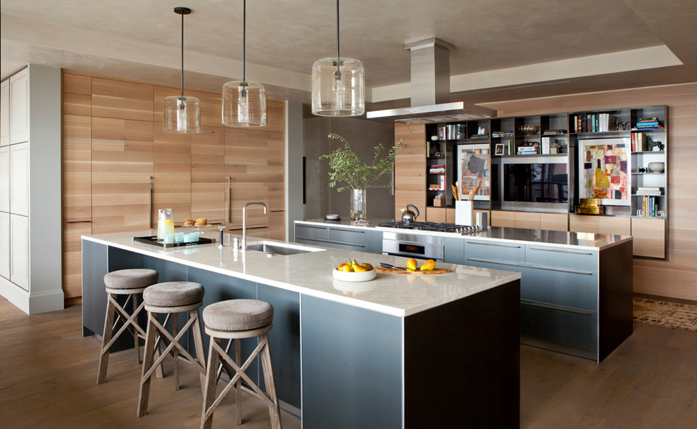 Geräumige Moderne Küche in U-Form mit Unterbauwaschbecken, Elektrogeräten mit Frontblende, braunem Holzboden, zwei Kücheninseln, flächenbündigen Schrankfronten, hellen Holzschränken und Marmor-Arbeitsplatte in Austin
