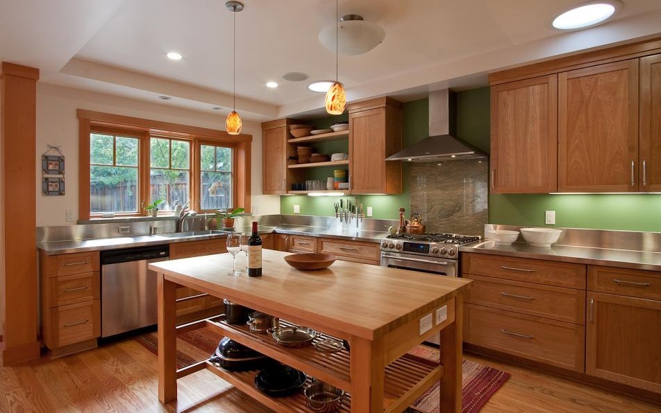 Inspiration for a mid-sized contemporary u-shaped medium tone wood floor open concept kitchen remodel in San Francisco with a farmhouse sink, flat-panel cabinets, medium tone wood cabinets, stainless steel countertops, green backsplash, mirror backsplash, stainless steel appliances and an island