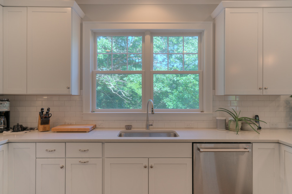 Inspiration for a medium sized traditional l-shaped enclosed kitchen in DC Metro with a submerged sink, shaker cabinets, white cabinets, composite countertops, white splashback, metro tiled splashback, stainless steel appliances, medium hardwood flooring and a breakfast bar.