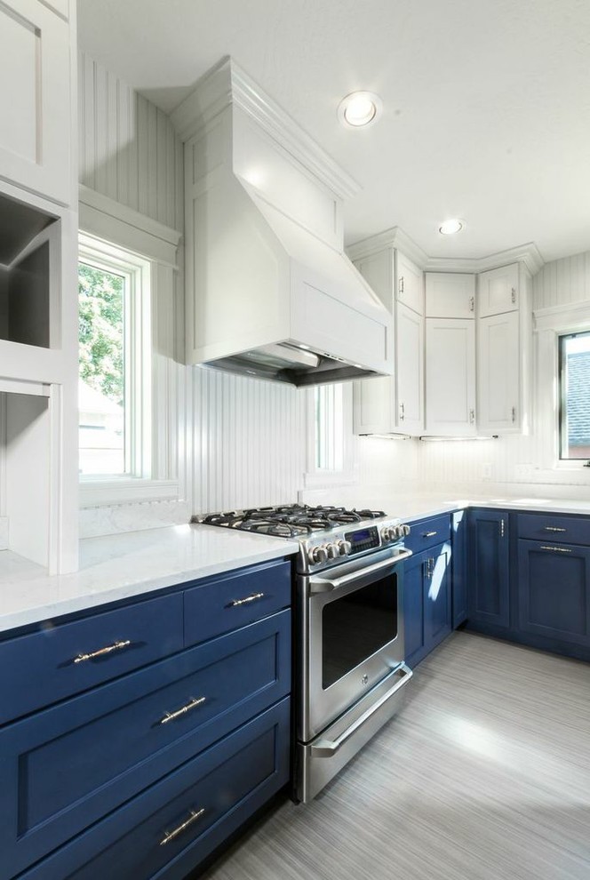 Foto di una grande cucina classica chiusa con lavello sottopiano, ante in stile shaker, ante blu, top in superficie solida, paraspruzzi bianco, elettrodomestici in acciaio inossidabile e pavimento in bambù