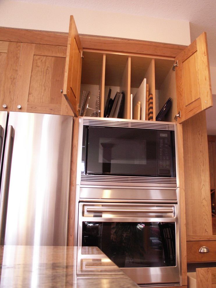 Bild på ett vintage kök, med skåp i shakerstil, skåp i mellenmörkt trä, granitbänkskiva, beige stänkskydd, stänkskydd i porslinskakel och rostfria vitvaror