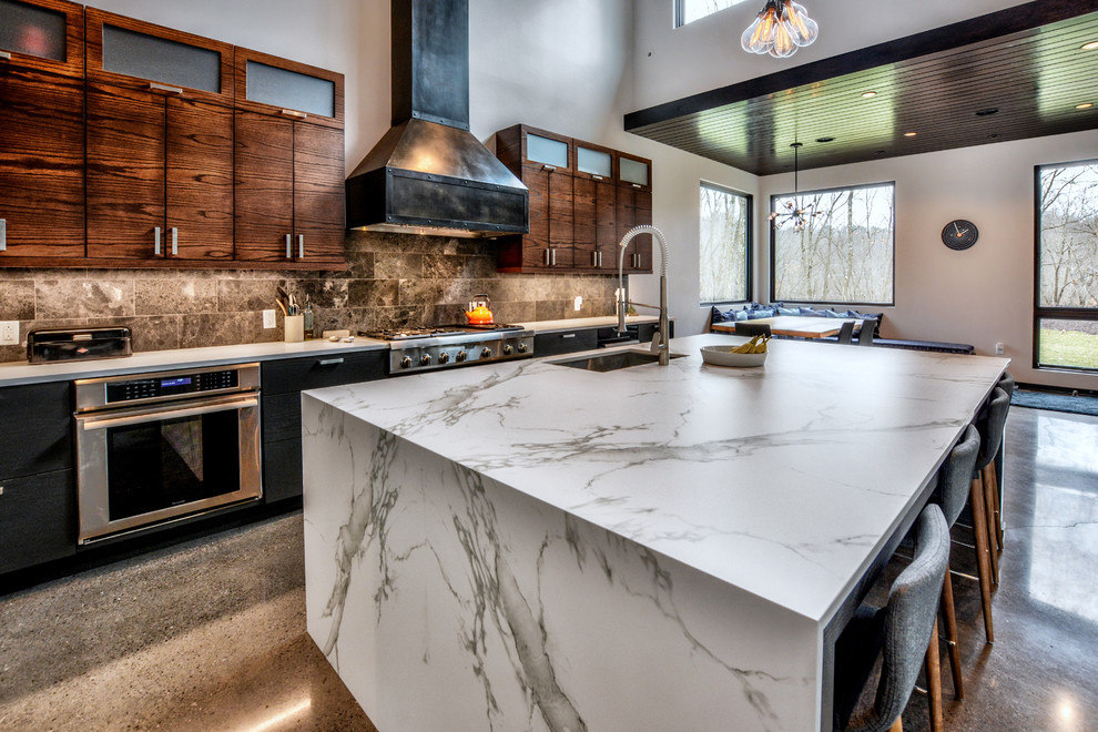 Open concept kitchen - large contemporary l-shaped concrete floor and gray floor open concept kitchen idea in Other with an undermount sink, flat-panel cabinets, dark wood cabinets, quartz countertops, gray backsplash, stone tile backsplash, stainless steel appliances and an island
