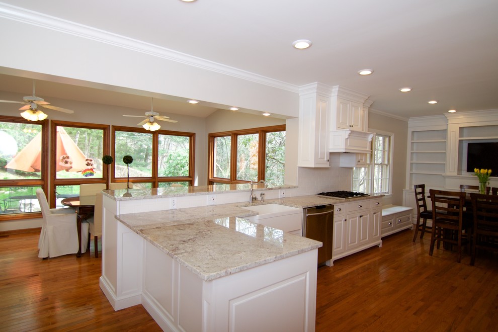 Mid-sized elegant u-shaped light wood floor eat-in kitchen photo in Other with a farmhouse sink, raised-panel cabinets, white cabinets, granite countertops, white backsplash, subway tile backsplash, stainless steel appliances and a peninsula
