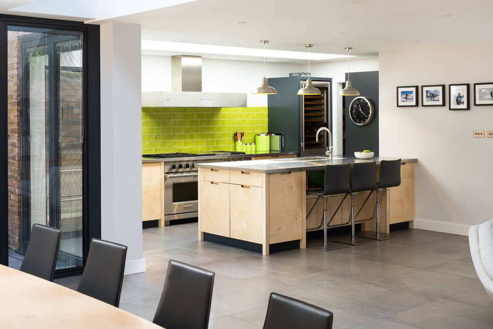Design ideas for a contemporary galley kitchen/diner in Surrey with flat-panel cabinets, light wood cabinets, green splashback, metro tiled splashback, stainless steel appliances, a breakfast bar, grey floors and grey worktops.