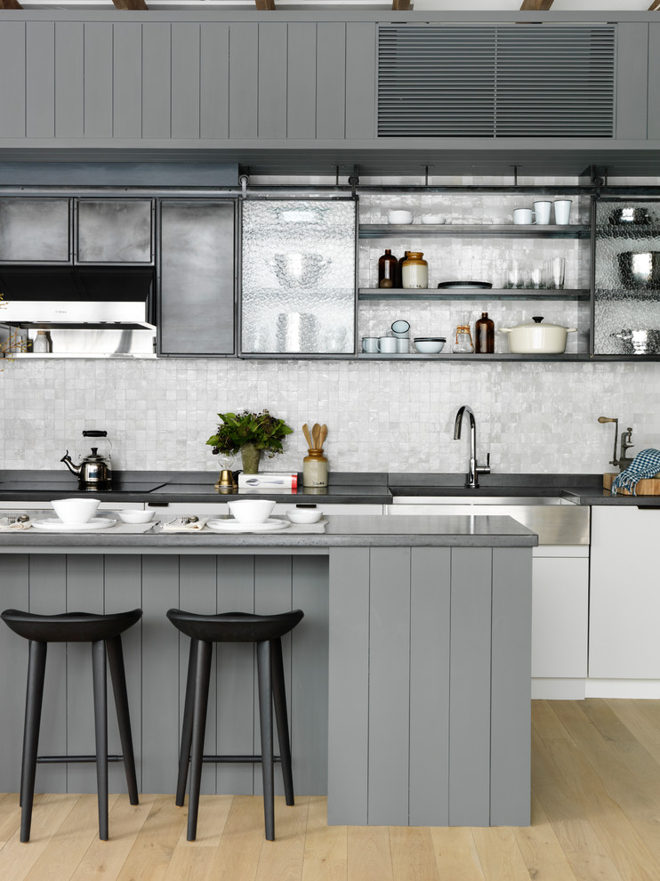 Klassische Küchenbar mit Landhausspüle, offenen Schränken, Küchenrückwand in Grau, hellem Holzboden und Kücheninsel in New York