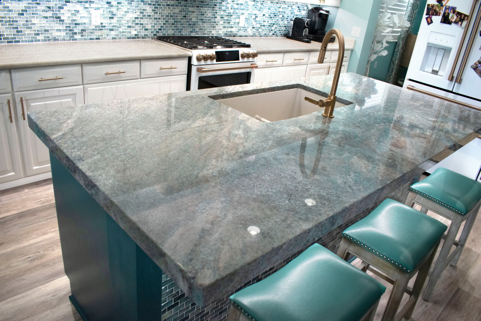 Exemple d'une cuisine moderne avec un évier encastré, un plan de travail en granite, une crédence bleue, une crédence en carreau de verre, îlot et un plan de travail bleu.