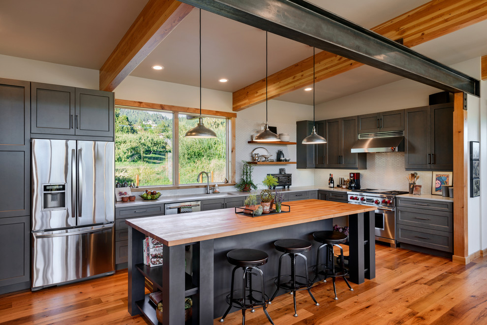 Inspiration for a country l-shaped medium tone wood floor kitchen remodel in Seattle with shaker cabinets, gray cabinets, white backsplash, stainless steel appliances and an island