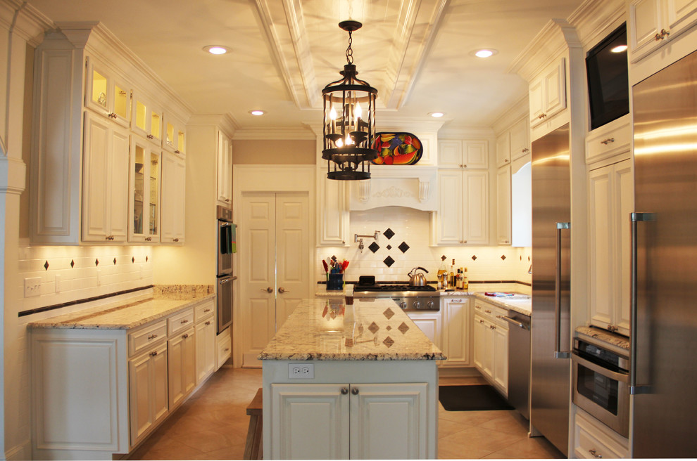 Medium sized classic u-shaped kitchen/diner in New Orleans with a submerged sink, raised-panel cabinets, white cabinets, stainless steel appliances and an island.