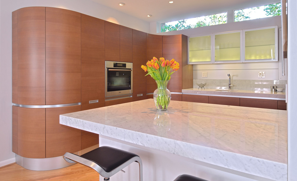 Example of a minimalist kitchen design in DC Metro with an undermount sink, medium tone wood cabinets, marble countertops, stone slab backsplash and paneled appliances